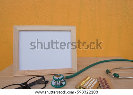 photo Frame and stethoscope on a wooden on Yellow background . Concept for health.