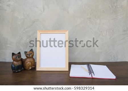 photo Frame on a wooden table and book and toy cat on Gray wall background .