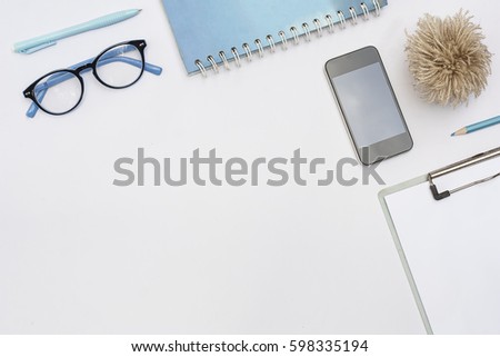 White office desk table, business and education concept with light blue office accessories, (Clipping path)blank screen smartphone, Top view with copy space.