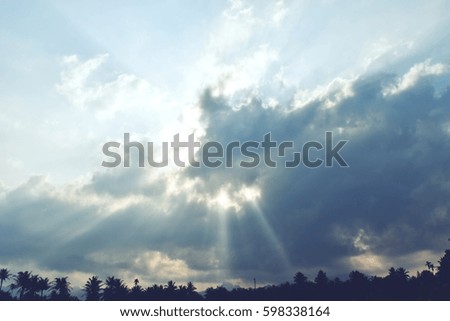 Sunlight or Beam shooting from behind the cloud down to  trees  silhouette,Photos back - light at the horizon began to turn orange color, Dramatic cloudscape area,Sunbeam,Thailand 