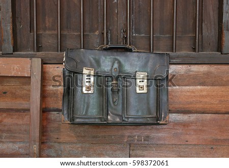 Old leather school bag hanging in wooden classroom background.