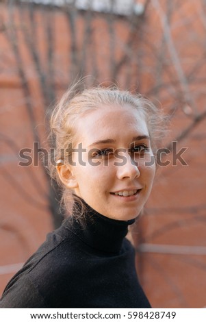 Close up portrait of blonde girl in black top.