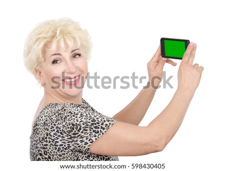 Cheerful blonde middle aged woman captures photo by mobile phone with green screen. Side view of woman in leopard print t-shirt with short sleeve. Mid-shot horizontal portrait on white background