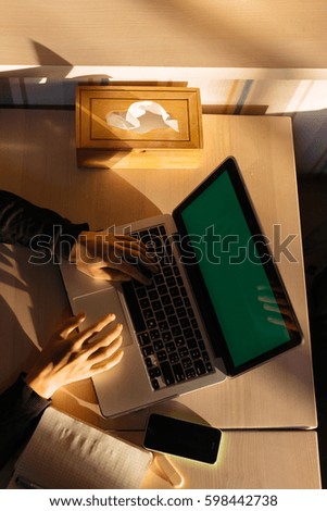 laptop with green screen and woman hands on keyboard