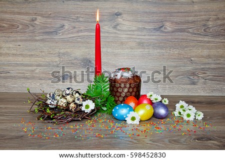 Easter composition with eggs, nest, Easter cakes, candle and flowers on wooden background. Spring festival Happy Easter. The natural background.