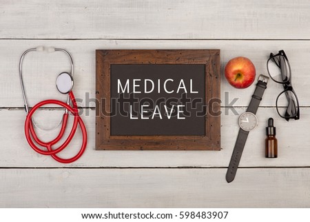 Medecine concept - blackboard with text "Medical leave", eyeglasses, watch and stethoscope on white wooden background Royalty-Free Stock Photo #598483907