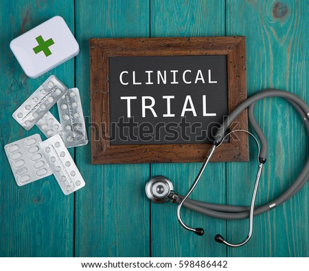 Medecine concept - Blackboard with text "Clinical trial", pills and stethoscope on blue wooden background Royalty-Free Stock Photo #598486442