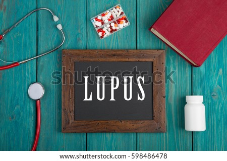 Medecine concept - Blackboard with text "Lupus", book, pills and stethoscope on blue wooden background Royalty-Free Stock Photo #598486478