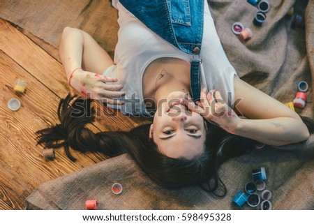 Woman lying on the floor paint all over her wooden background