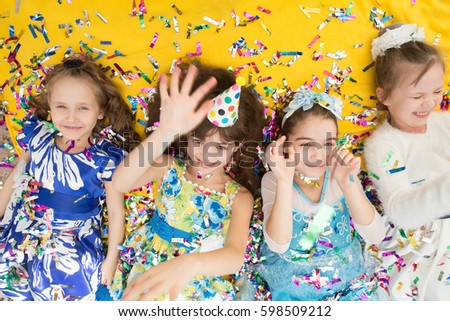 Happy children celebrating party with blowing confetti top view. The girls in birthday party.  Positive emotions. 

