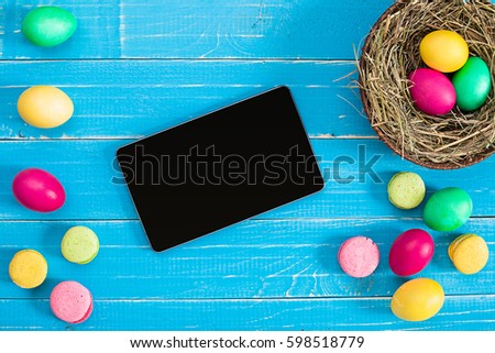 Colorful easter egg in nest on blue wood board.
