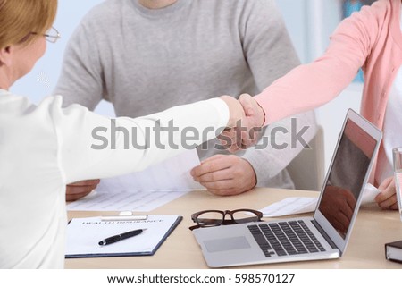 Women shaking hands sitting at workplace in light office