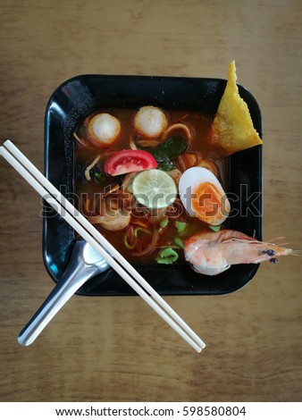 Tom Yum Goong in Thailand, fish noodle and shrimp hot and spicy in black bowl