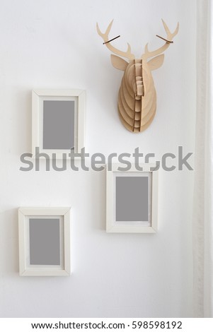 three empty picture frames on wall next to decorative fake antler