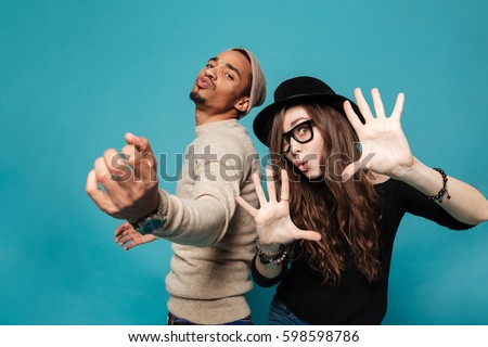 Portrait of a funny young modern couple dancing and having fun together over blue background Royalty-Free Stock Photo #598598786