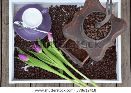 Purple coffee mug in tray with antique coffee machine, three tulip and Coffee beans and table wooden background