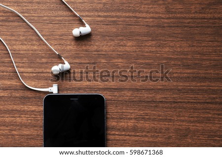 White headphones and smart phone on wooden red table background