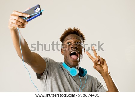 young afro american black man smiling happy taking selfie self portrait picture with mobile phone looking excited having fun posing cool isolated in grey  background in communication technology