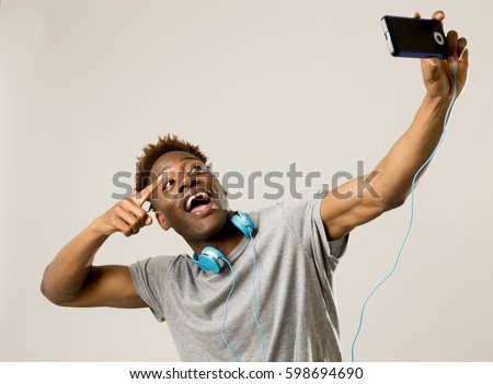 young afro american black man smiling happy taking selfie self portrait picture with mobile phone looking excited having fun posing cool isolated in grey  background in communication technology