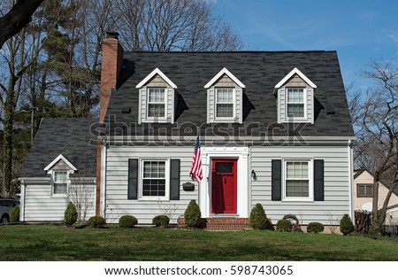 Cape Cod House with Three Dormers & Red Door Royalty-Free Stock Photo #598743065