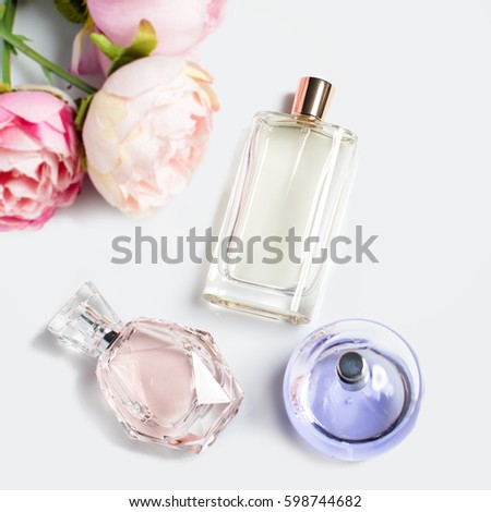 Perfume bottles with flowers on light background. Perfumery, cosmetics, fragrance collection. Flat lay Royalty-Free Stock Photo #598744682
