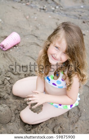 Happy little girl playing in sand at beach, shallow depth of field