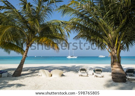 Palms shade on white beach with turquoise water