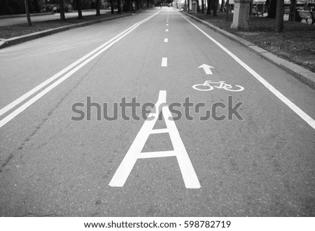 Black and white background with separate bicycle lane for cycling in the park.Symbol painted on asphalt with white paint.No models.Bike pathway for riding healthy city transport