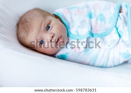Cute adorable newborn baby wrapped in colorful blanket, looking at the camera. Closeup of peaceful child, little baby girl after sleeping. Family, Birth, new life. Swaddling as method for calm child Royalty-Free Stock Photo #598783631