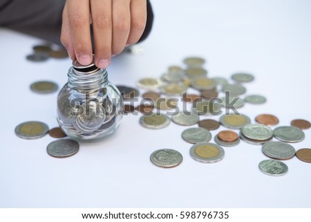 Asian child putting coin in glass jar for money saving,financial concept
