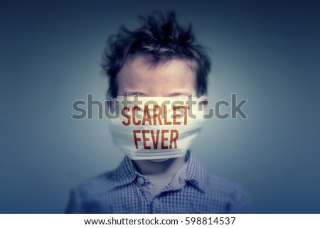 Boy in a medical mask with red inscription SCARLET FEVER on his face in the dark