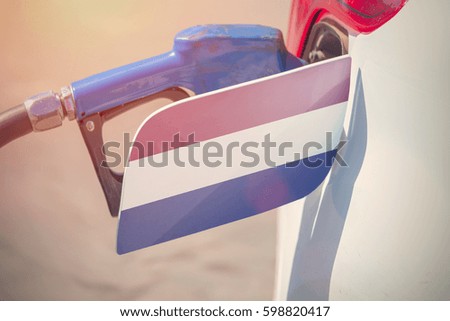 Flag of Denmark on the car's fuel filler flap with gas pump nozzle in the tank