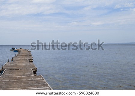 Blue sea with boat and wooden pier landscape. Minimalist seaside view toned photo. Rustic timber pierce in still sea. Wanderlust seascape trendy banner template with text place. Seashore background