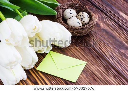 Bouquet white  tulip flowers with easter eggs on old wooden table.Place for text.