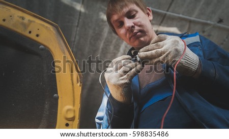 Automotive electrician checks electro relay in car, small business - auto garage service, bottom view Royalty-Free Stock Photo #598835486