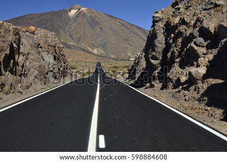 Road to Teide volcano trough lava stone with the Crater from the latest outbreak in background against a blue sky, picture from Tenerife Spain.