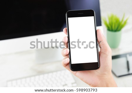 close-up hand hold phone showing white blank screen over work desk