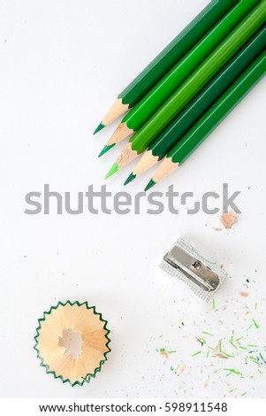 five green wooden pencils and sharpener on white