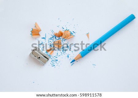 blue wooden pencil, sharpener and blue pencil shavings on white