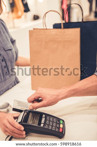Cropped image of handsome man paying with credit card while doing shopping in the mall