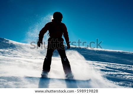 the snowboarder siluette is on blue sky background is riding on the mountain or hill