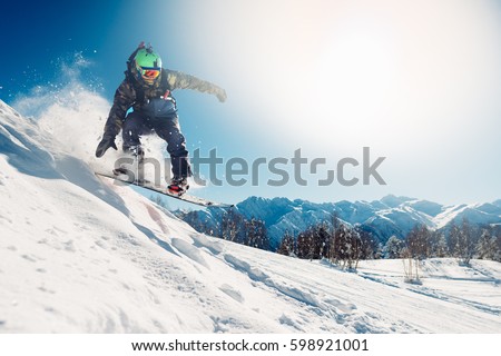 snowboarder is jumping with snowboard from snowhill Royalty-Free Stock Photo #598921001
