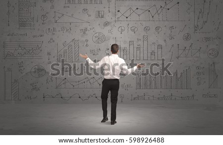 A successful confident businessman thinking about decisions, standing in front of wall full with graph pie charts and calculations concept