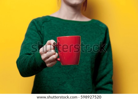 beautiful young woman hand holding a red cup of the wonderful yellow background