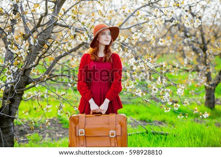 beautiful young woman with suitcase on the wonderful blooming trees background