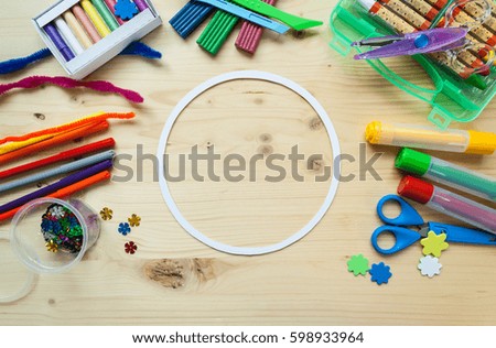 Round frame with colorful pencils scissors on wood background, space for text, flat lay, back to school concept