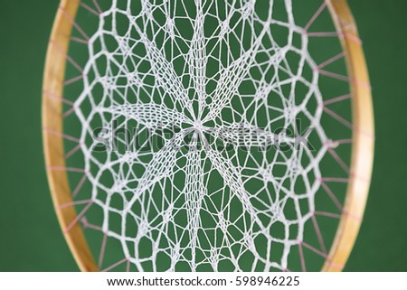 ancient native american dream catcher with white handmade crochet doily on dark green background Tribal amulet, lace, wooden circle
