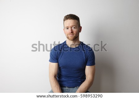 Portrait of cool young guy sitting close to white background.
