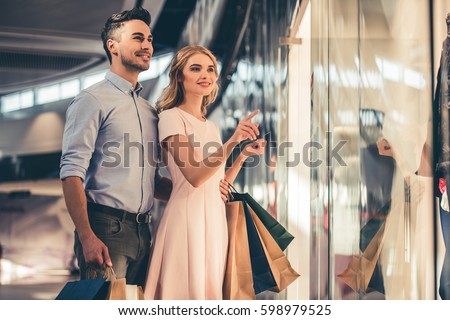 Beautiful couple with shopping bags is talking and smiling while doing shopping in the mall Royalty-Free Stock Photo #598979525