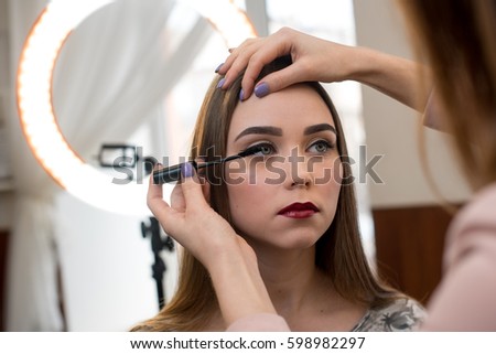 A professional make-up artist paints eyelashes models in the studio.